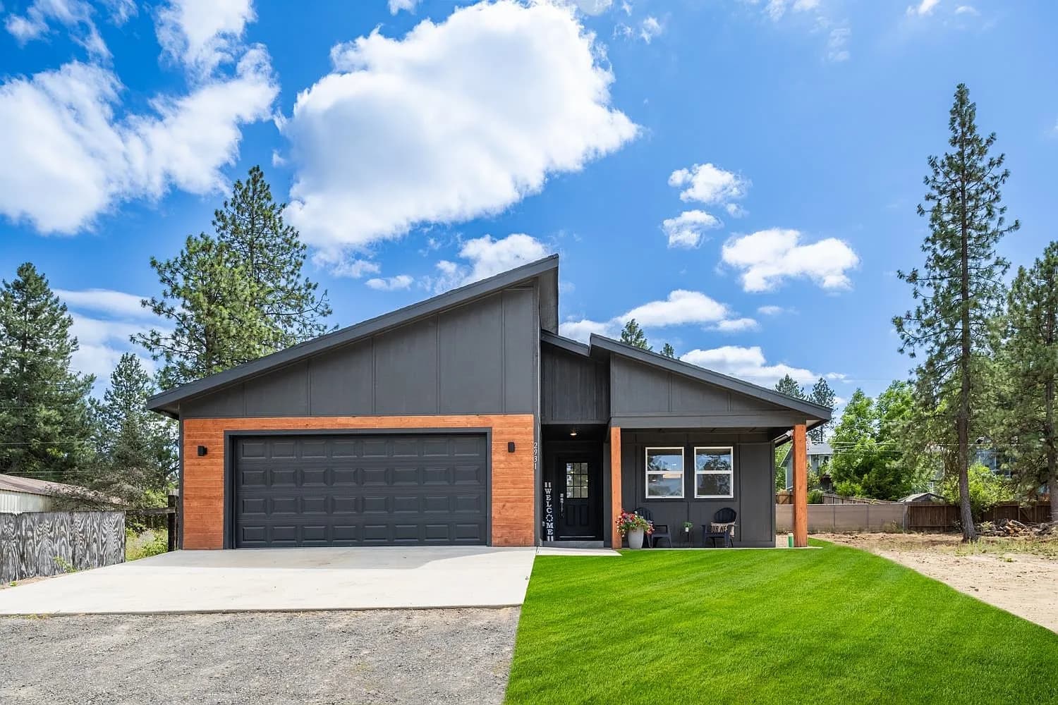 Charcoal board-and-batten custom home with warm timber accents, a shed roof, and a two-car garage