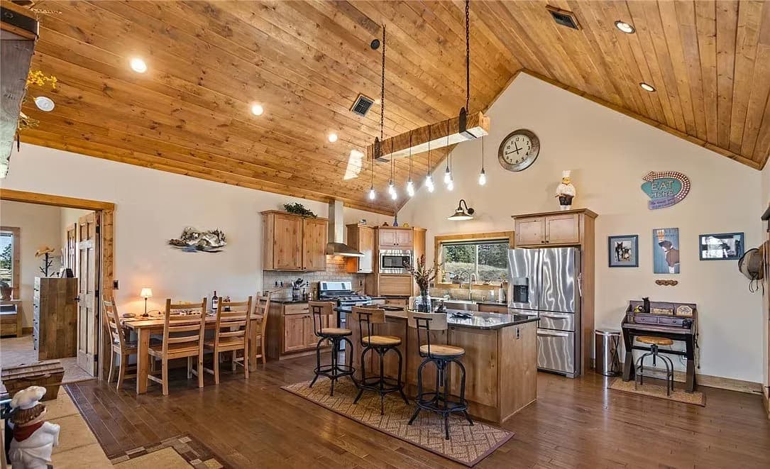 Kitchen with knotty pine cabinets, a vaulted wood ceiling, and a granite island under a beam light