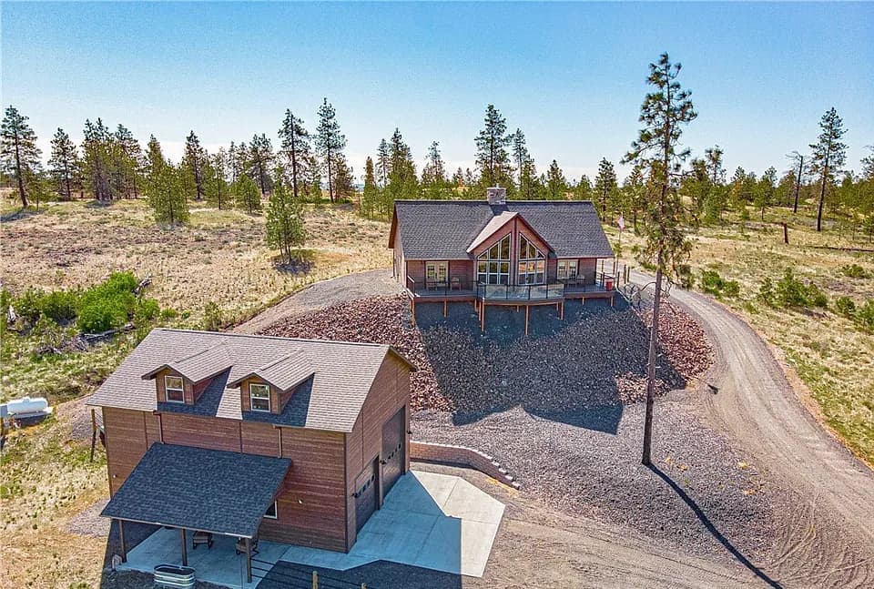 Acreage custom home and detached shop on a pine-dotted hillside, typical of builds near Cheney