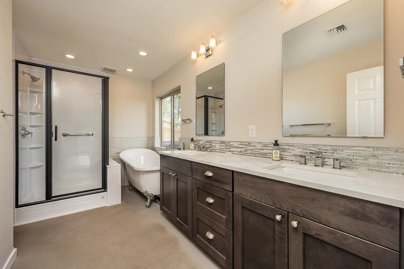 Primary bathroom with a dark wood double vanity, soaking tub, and black-framed walk-in shower