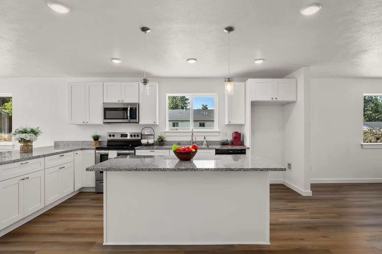 White shaker kitchen with a center island, granite counters, stainless appliances, and pendant lights