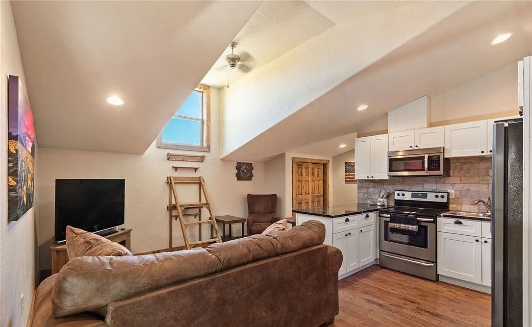 Guest suite with a vaulted ceiling, compact kitchen, and living area under a high window