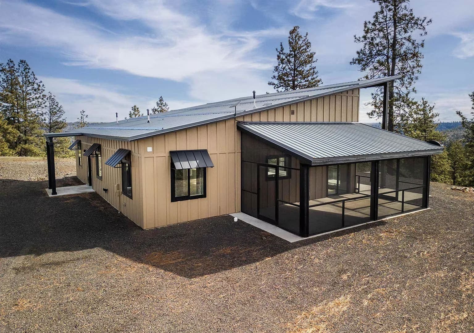 Tan board-and-batten custom home with a metal roof, window awnings, and a black screened porch